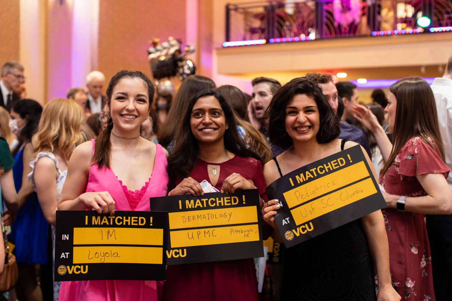 Three residents holding their match posters up