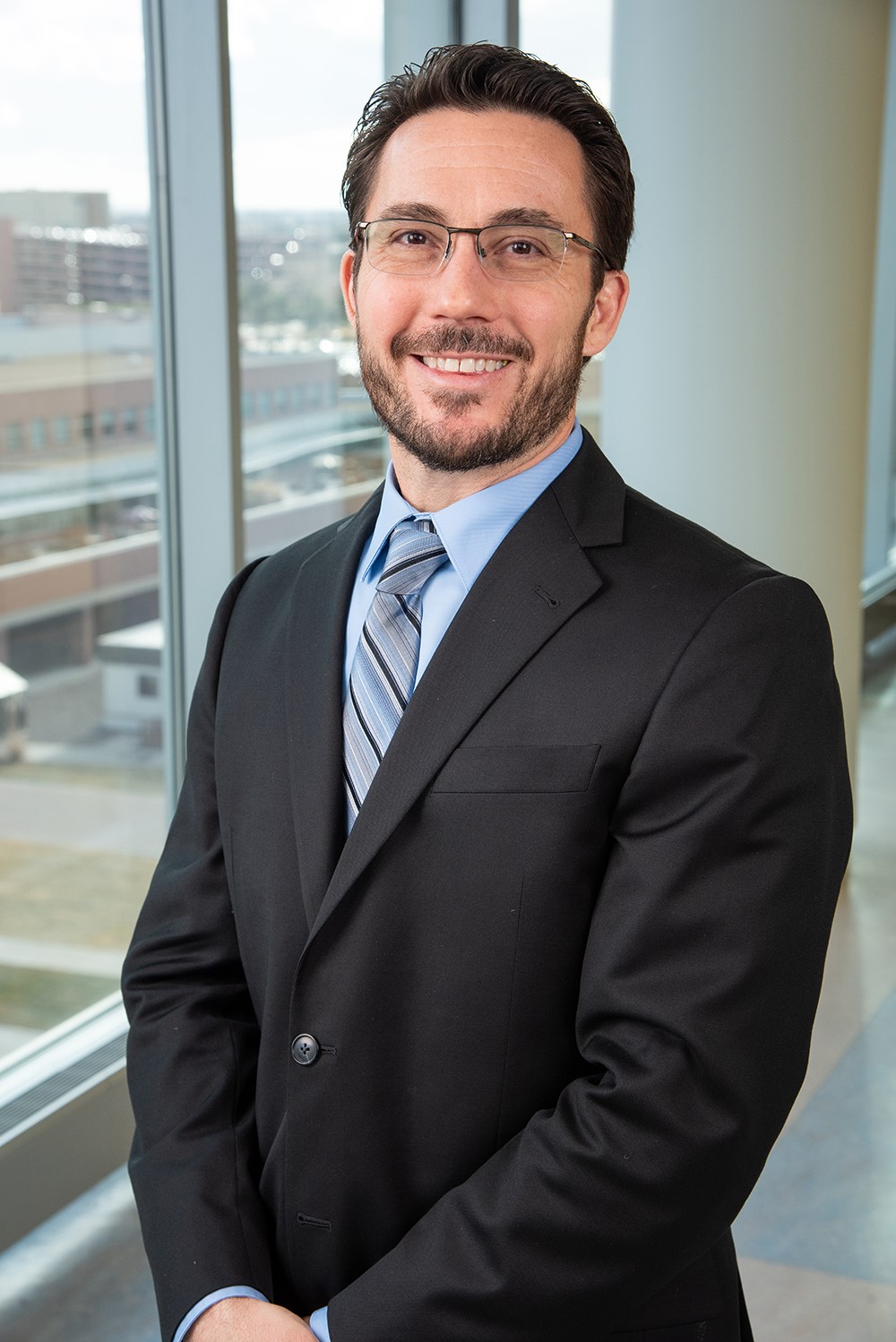 Brian Berman, M.D., stands smiling next to a window