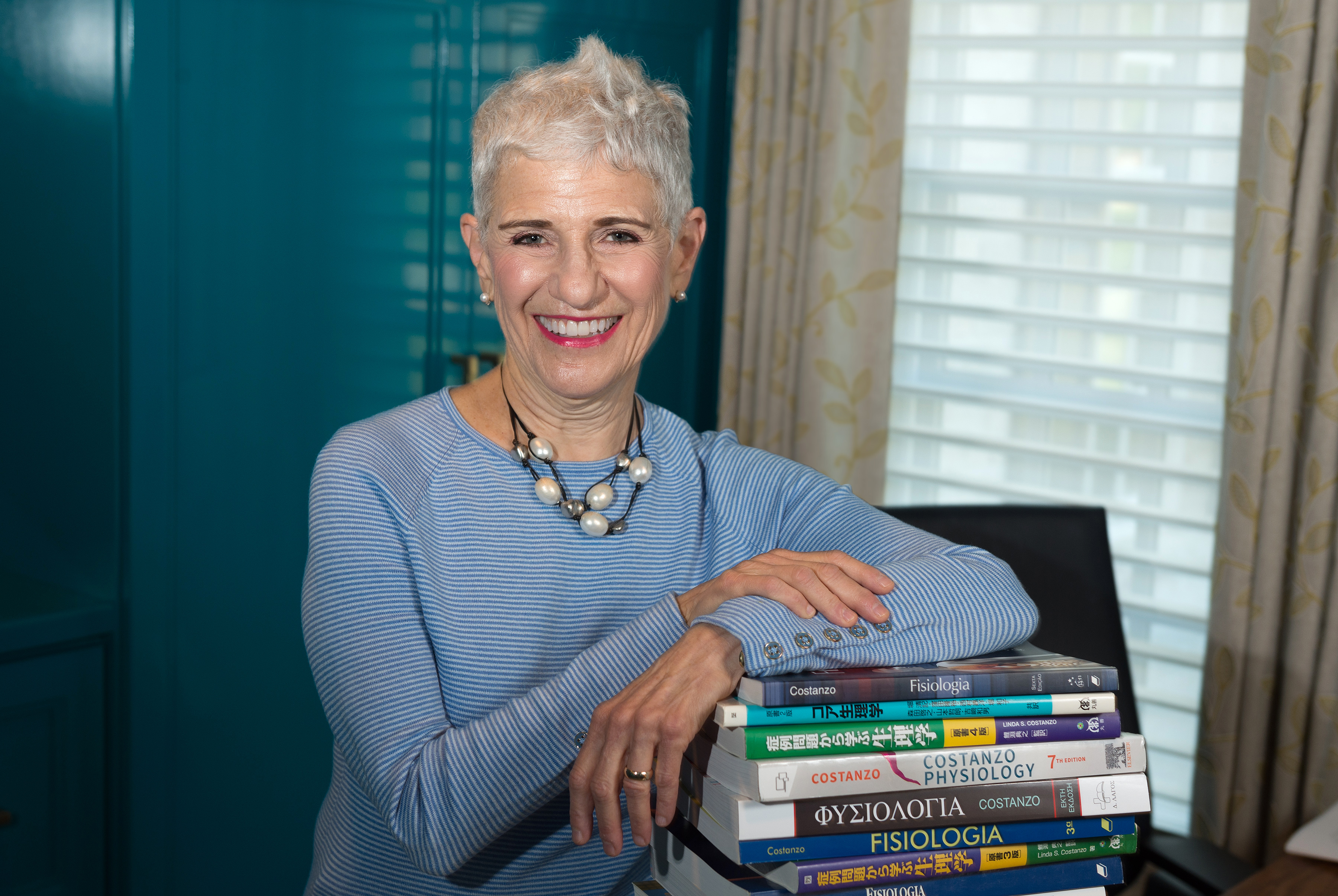Linda Costanzo PHD leaning on stack of books