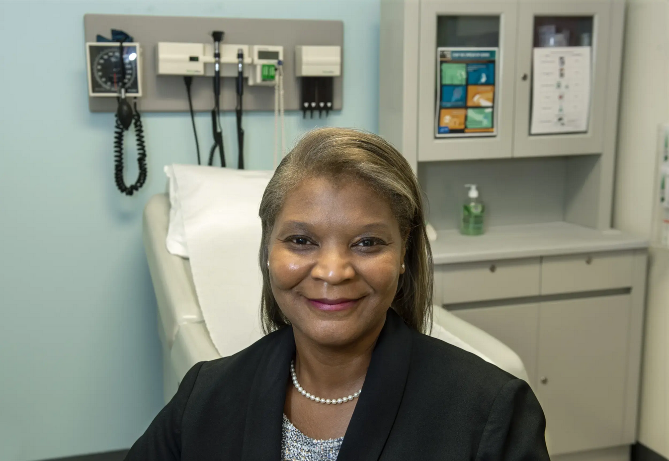 A woman wearing a suit jacket smiling in an exam room