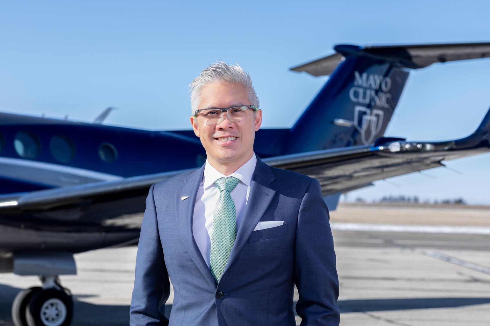 Man wearing blue suit stands in front of airplane