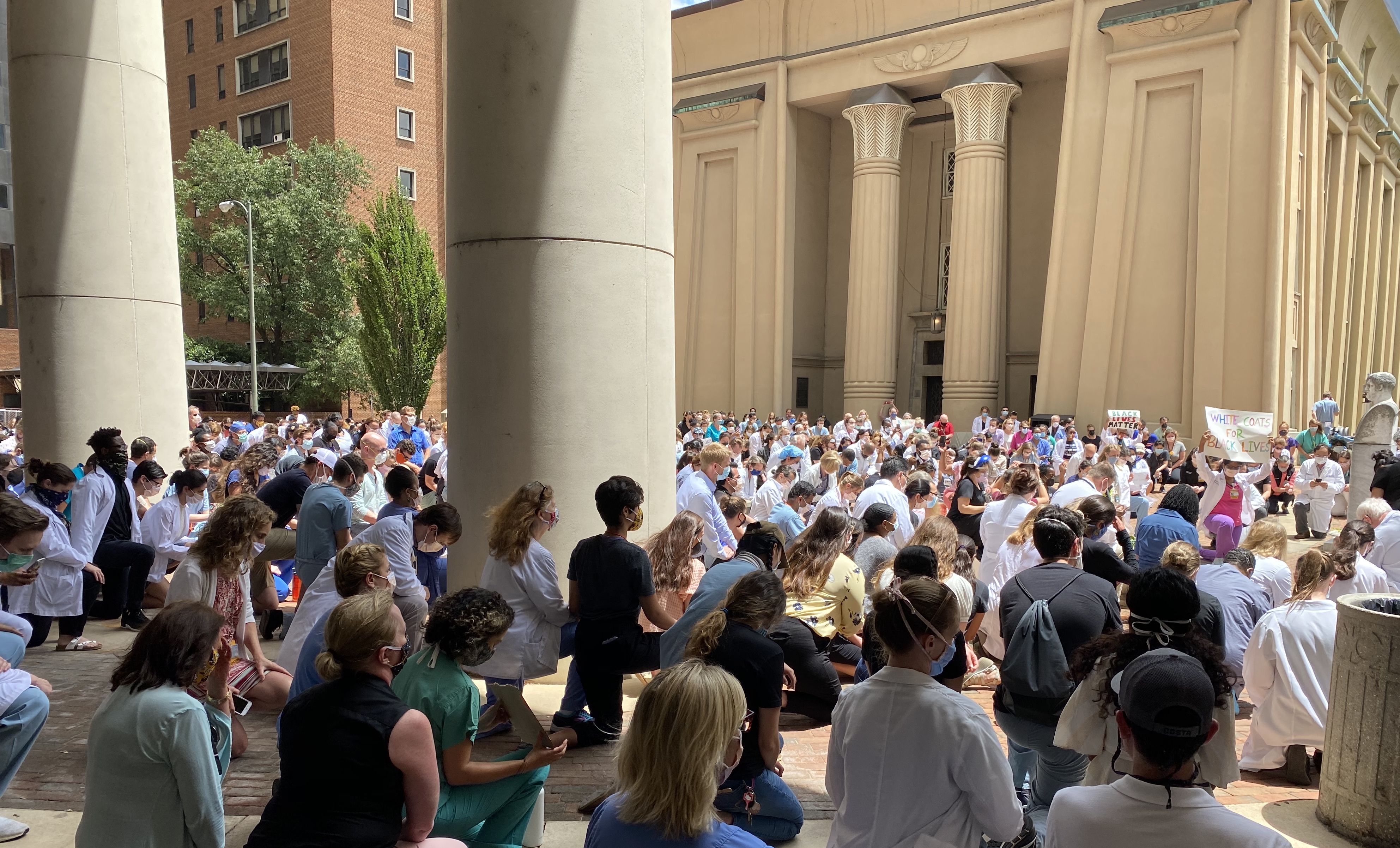Students, faculty and VCU Health clinicians kneel in silent reflection in front of the Egyptian Building.