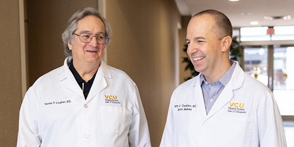 Two physicians in white coats walking down a hallway