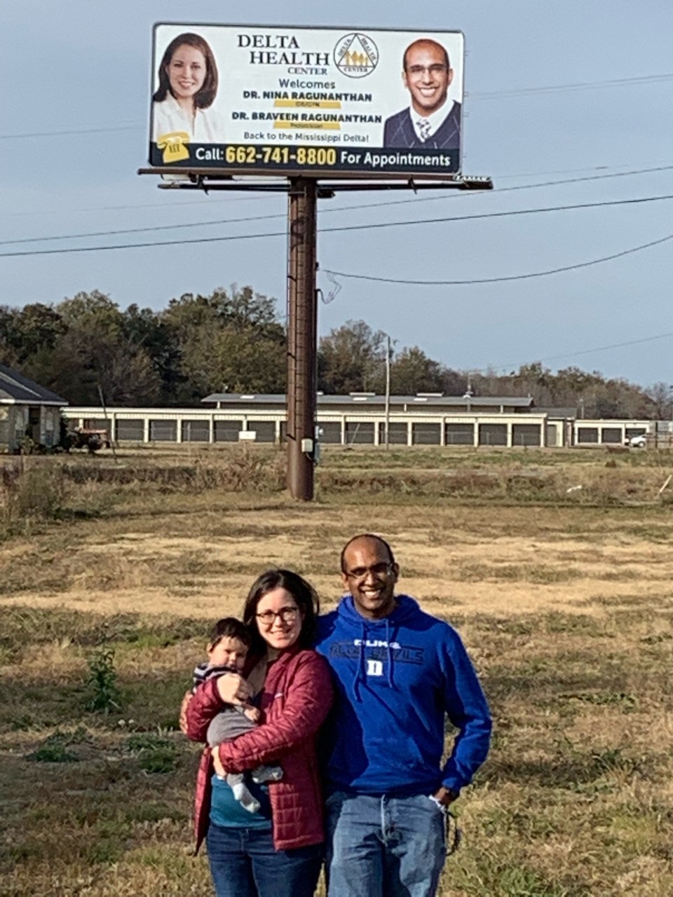 M17 Braveen Ragunanthan stands with his wife and baby in front of a billboard promoting their arrival in rural Mississippi