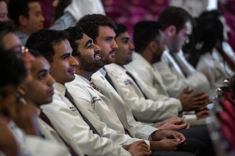 A row of new doctors listening to the white coat ceremony 
